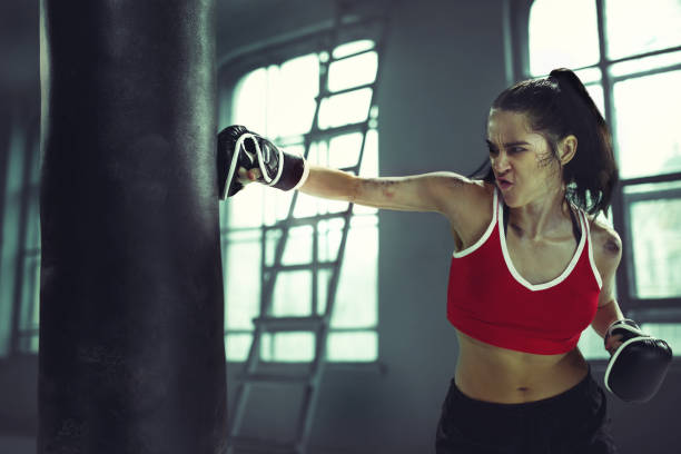 istock Young woman boxing workout in an old dark gym 940485356