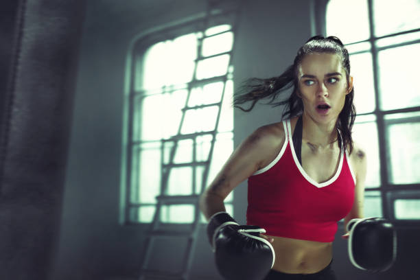 istock Young woman boxing workout in an old dark gym 940485410