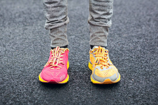 piernas en zapatos multicoloras. - pair fotografías e imágenes de stock