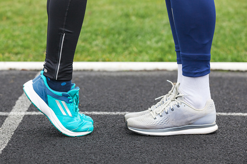 Cropped shot of a male and female legs in running shoes standing close to each other. Love concept image.