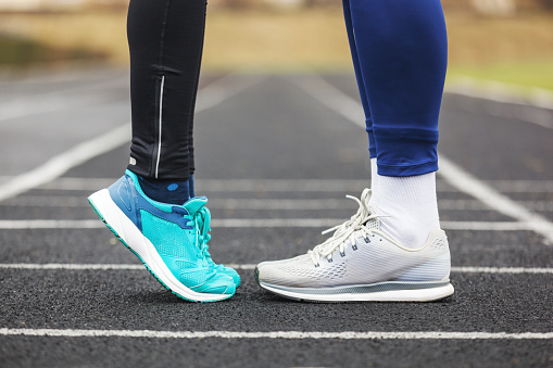 Cropped shot of a male and female legs in running shoes standing close to each other. Love concept image.