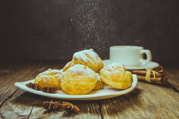 istock Delicious eclairs sprinkled with icing sugar, stand on a wooden table. Copy spase. 940488792