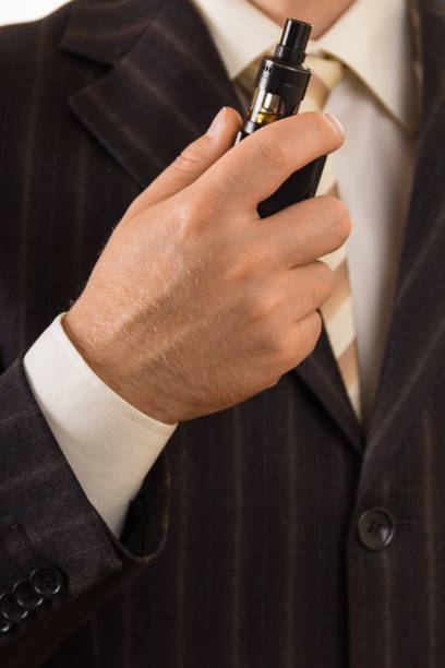 istock Man in a suit with electronic cigarette in hand 940491846