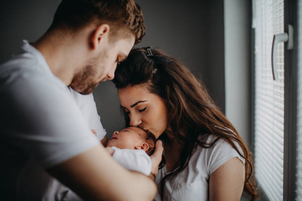 padres joven sonrientes con su niña en casa - newborn fotografías e imágenes de stock