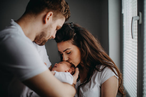 Smiling young parents with their baby girl at home Smiling young parents with their baby girl at home new baby stock pictures, royalty-free photos & images