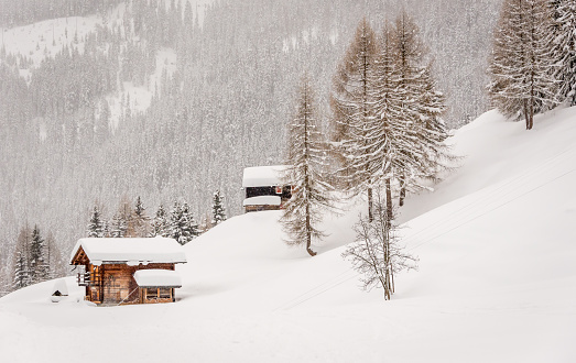 Winter in the Swiss alps, wooden chalets covered in fresh snow on the side of a ski slope.