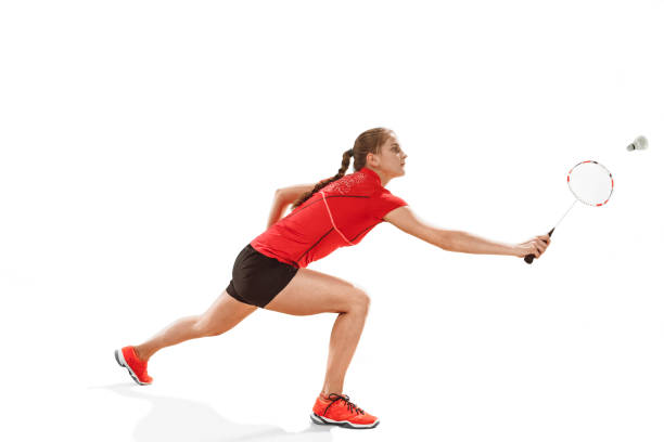 istock Young woman playing badminton over white background 940509472