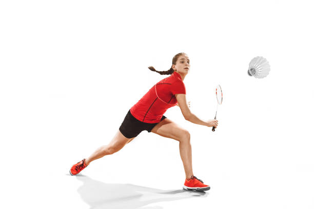 Young woman playing badminton over white studio background. Fit female athlete isolated on white. badminton player in action, motion, movement. attack and defense concept