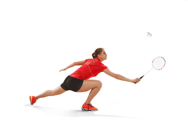 istock Young woman playing badminton over white background 940509656