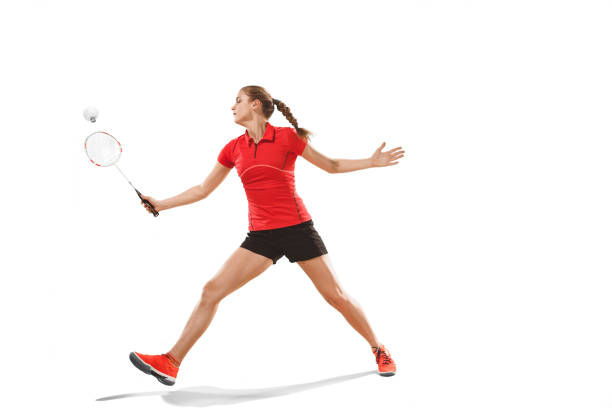 istock Young woman playing badminton over white background 940509696