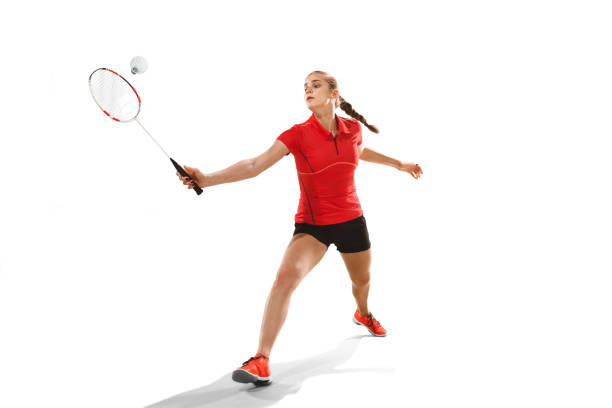 istock Young woman playing badminton over white background 940509732