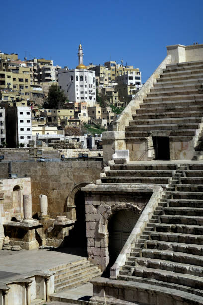 ruins of an ancient roman amphitheater in downtown amman, Jordan, with modern buildings alongside it on a nearby hillside