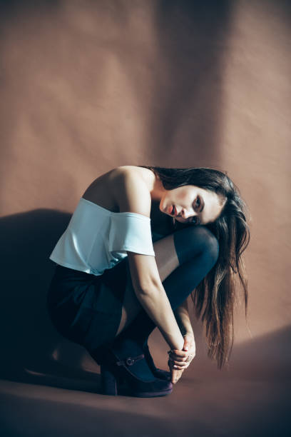 istock Young attractive woman posing on brown background sitting on squat 940516326
