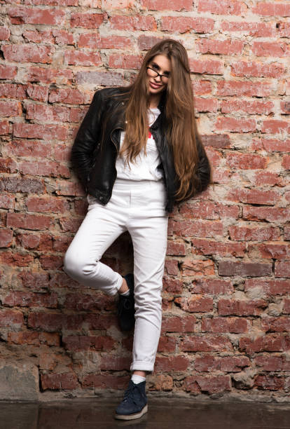 istock Young attractive woman posing against a brick wall. Stylish appearance, black leather jacket 940519770