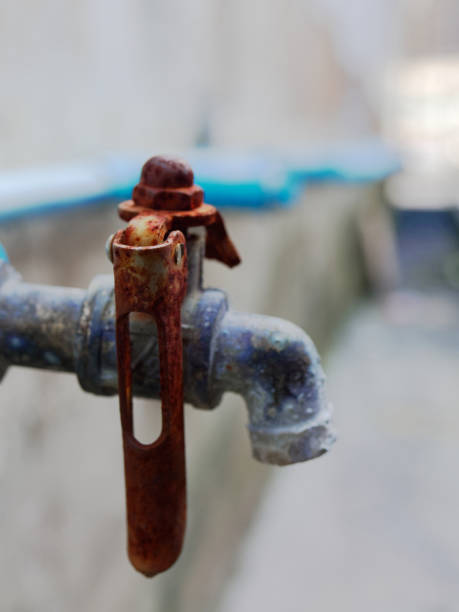 istock Old rustic faucet from blue plastic pipe with red handle and brass spout in retro or vintage style 940531848