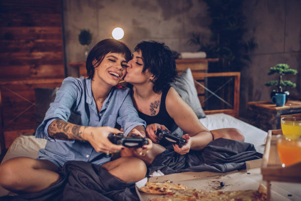 jouer aux jeux vidéos dans le lit - lesbian homosexual kissing homosexual couple photos et images de collection