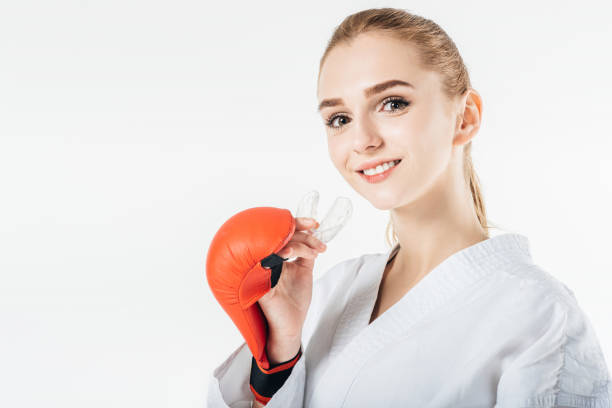 smiling female karate fighter holding mouthguard isolated on white smiling female karate fighter holding mouthguard isolated on white mouthguard stock pictures, royalty-free photos & images