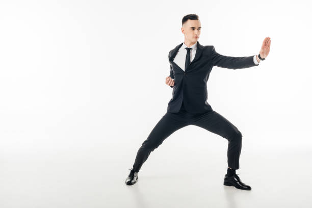istock handsome businessman standing in karate position in suit isolated on white 940536252