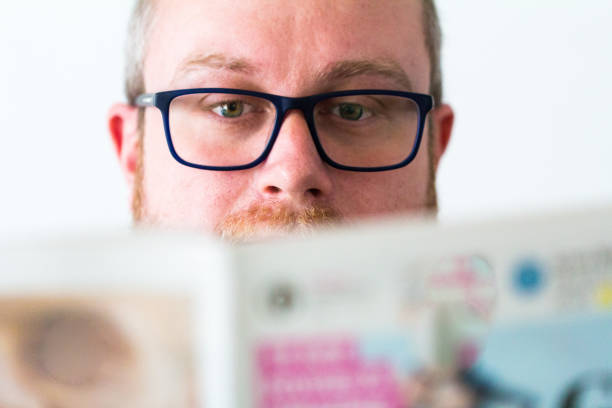 istock Close up of young man with glasses and beard reading newspaper 940536320