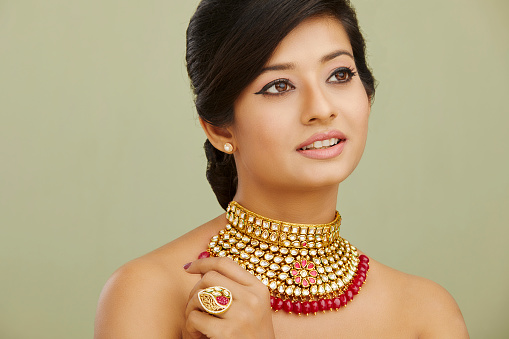 Pretty Indian young women portrait with beautiful jewelry against green background.