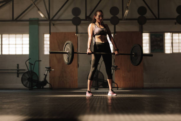 istock Fitness model performing weight lifting exercise at gym 940552262