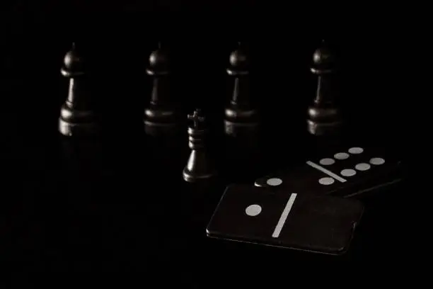Photo of black dice dominoes and chess pieces on a dark background