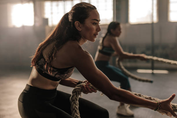 istock Fitness females pulling rope at gym 940555342