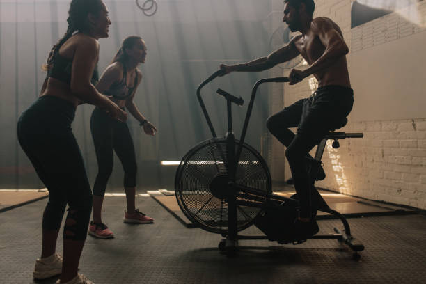 체육관에서 공기 자전거에 운동 하는 사람을 동기 부여 하는 두 여자 - spinning instructor exercising gym 뉴스 사진 이미지