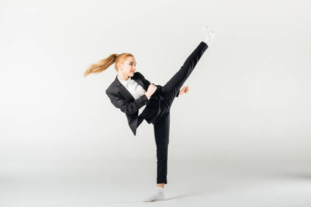 businesswoman performing kick in suit isolated on grey