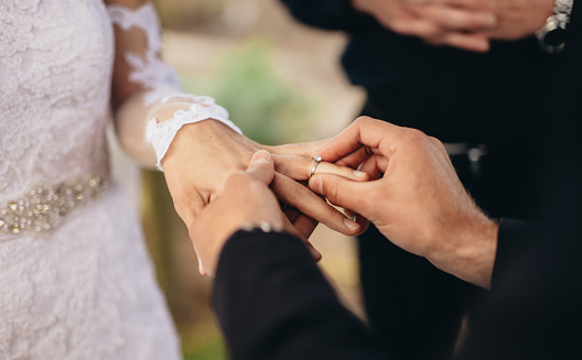 Hands, love and couple with diamond wedding ring shows trust, jewellery and support in a marriage commitment. People, jewelry and save the date event goals in engagement of bride and groom together