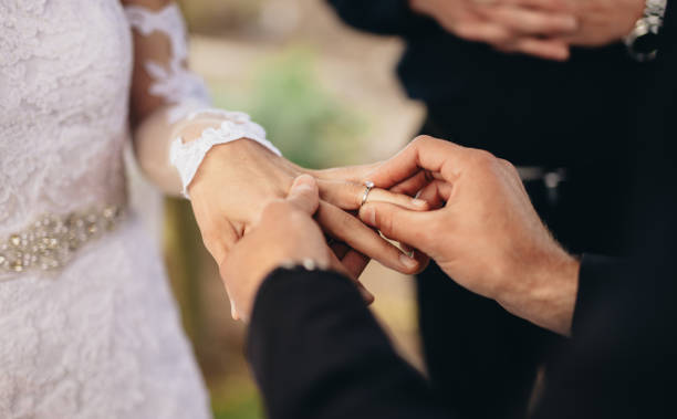 Couple exchanging wedding rings Closeup of groom placing a wedding ring on the brides hand.  Couple exchanging wedding rings during a wedding ceremony outdoors. traditional ceremony photos stock pictures, royalty-free photos & images