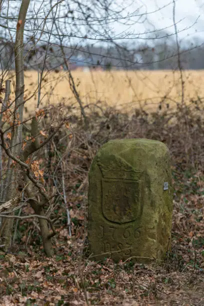 Historical boundary stone on the land border of Netherlands and Germany near the in Dutch called komiezenpaden paths in the past used by border guards and smugglers