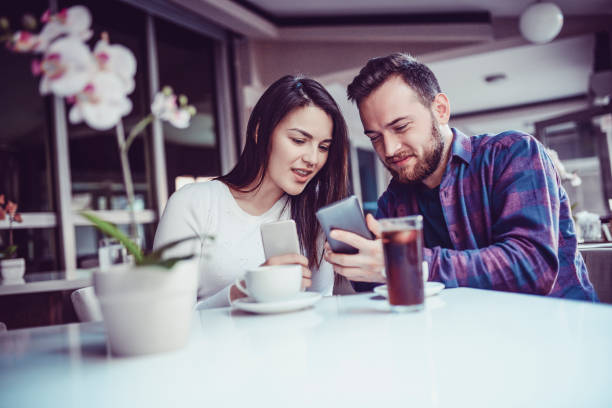 istock Cute Couple Transferring Data With Mobile Phone in Restaurant in the Morning 940576616