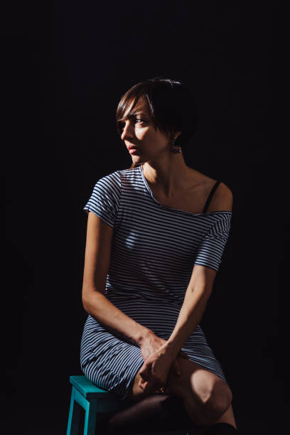 istock Brunette in a striped dress on a black background 940577488