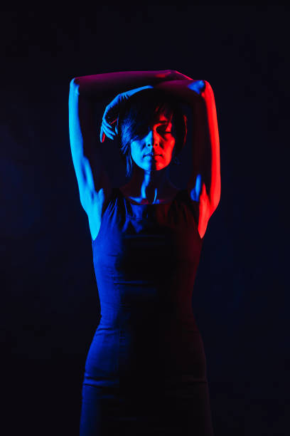 istock Brunette in a black dress on a black background. 940577640
