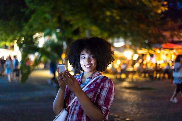 istock Smiling woman using smart phone on street at night 940586354