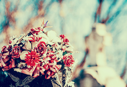 Artificial flowers with an old coloring treatment. In the background of the crosses.