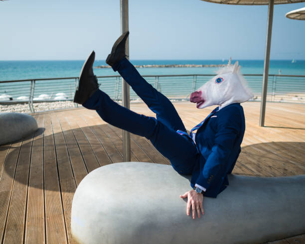 istock Young man in elegant suit falls down under umbrellas on the city waterfront 940598618