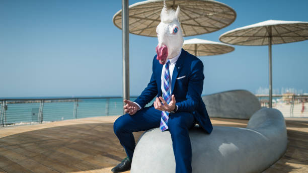 istock Young elegant man in suit sits under umbrellas on the city waterfront and active gesticulate 940598638