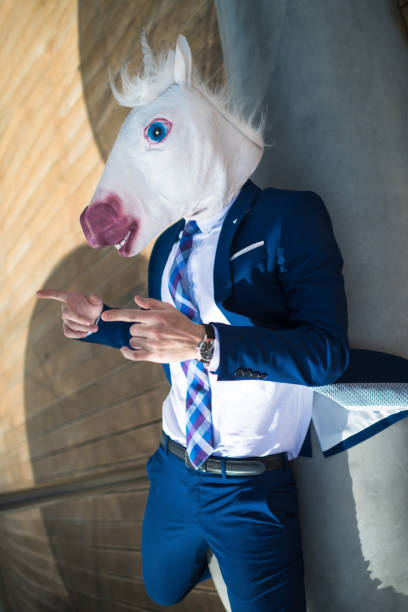 istock Young cool man in elegant suit and funny mask active gesticulate 940598640