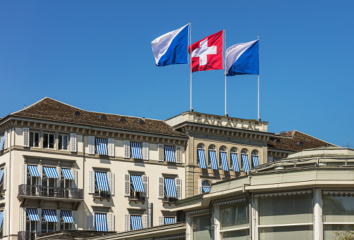 Zurich, Switzerland - 20 April, 2016: upper part of the Hotel Baur au Lac building decorated with flags of Zurich and Switzerland. The Hotel Baur au Lac is a luxurious hotel in Zurich, founded in 1844 by Johannes Baur.
