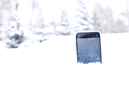 smartphone in snow in forest in winter time showing how many degrees outside