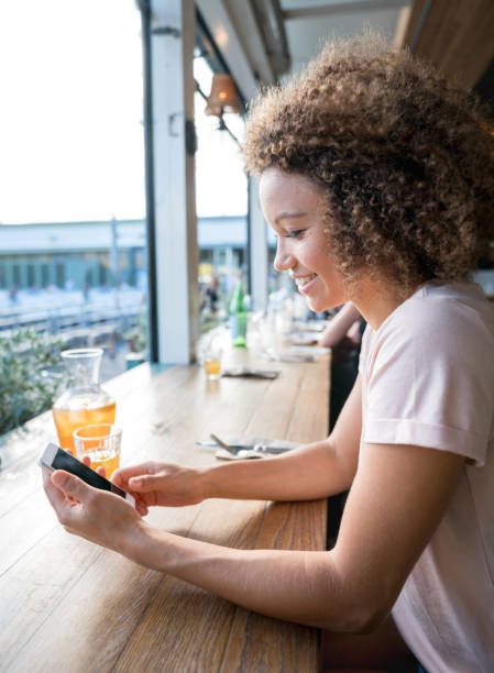 istock Woman at a cafeteria texting on her cell phone 940636318