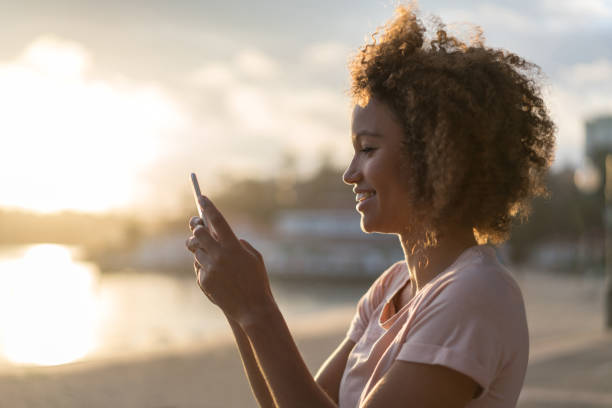 istock Casual woman texting on her cell phone at the beach 940636354