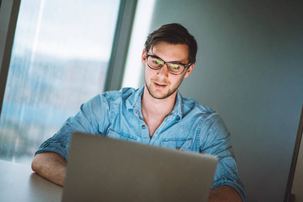 istock Young man with glasses looking at his laptop screen 940636722