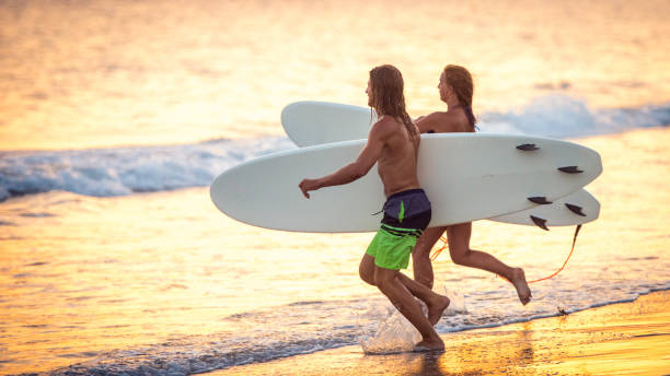 Pair of young surfers running towards the waves
