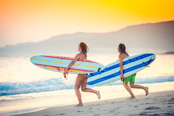istock Pair of surfers running towards the waves 940640524