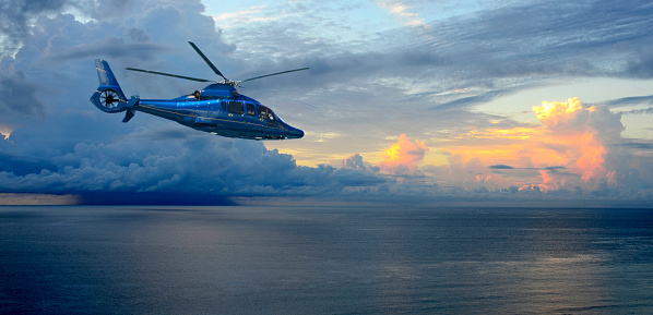 A helicopter flies by as Thunderstorms build over the Atlantic Ocean at sunrise in Palm Beach, Florida