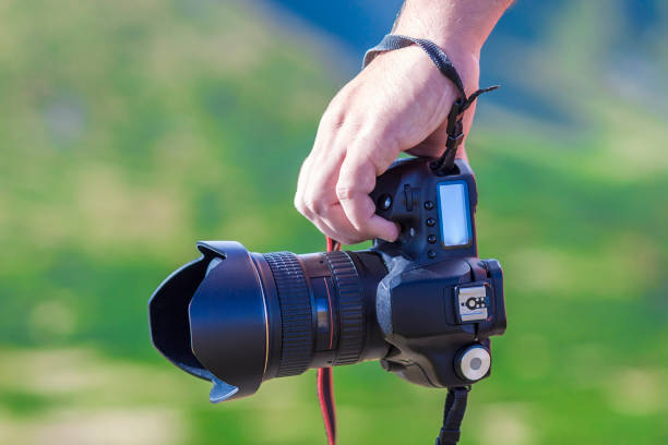 istock Hand of a man holding professional digital camera on blurred green background 940681180