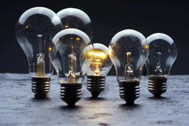 istock Burned light bulbs and one light bulb on a gray concrete background. 940686028